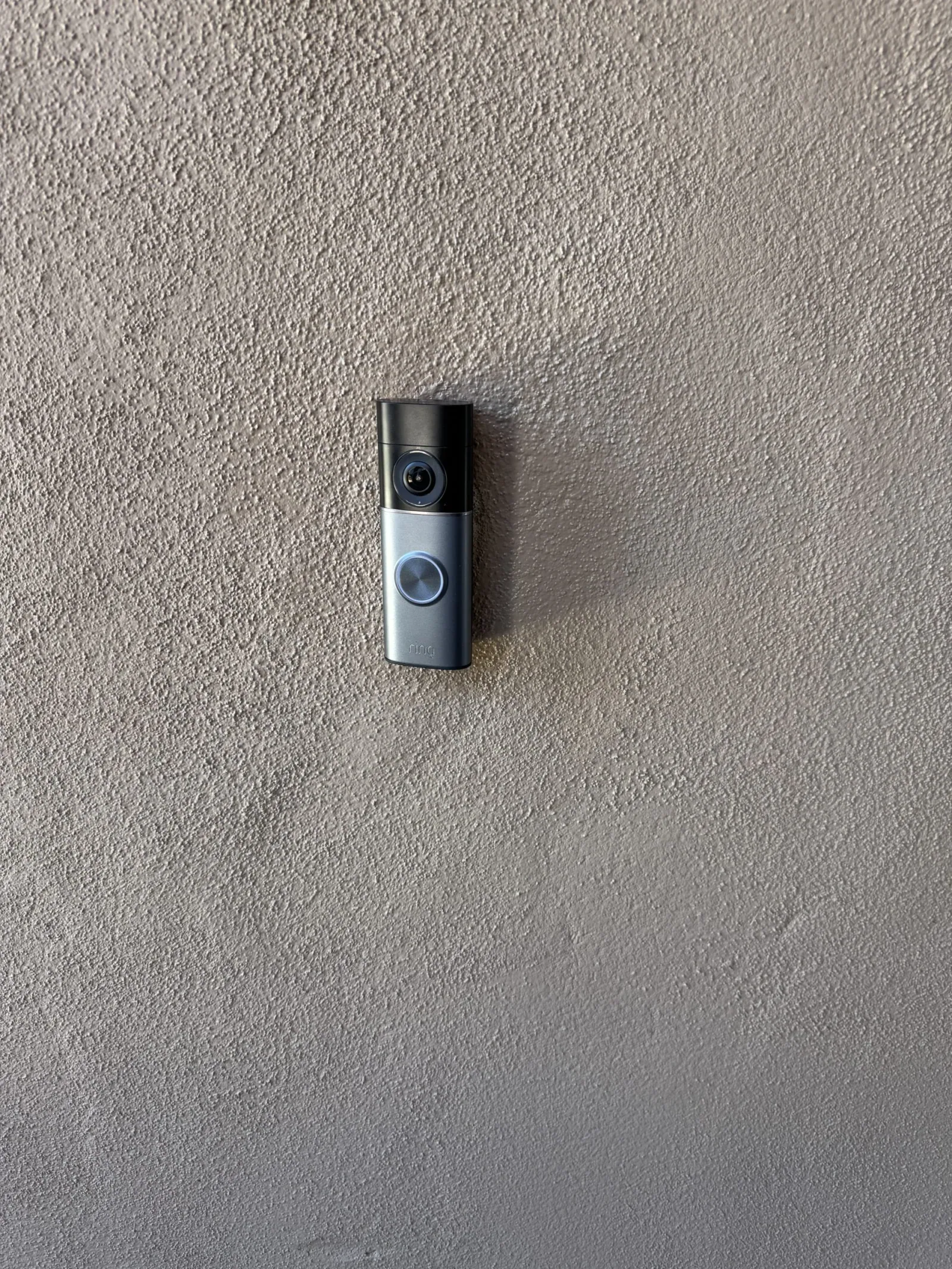 Ring video doorbell mounted level beside the entry on a stucco wall