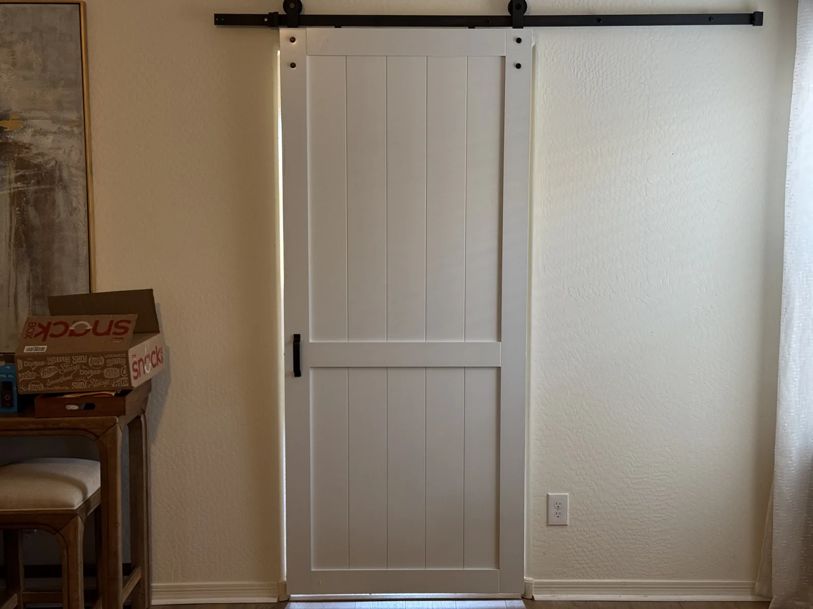 Finished white sliding barn door mounted level on black hardware in a Phoenix home